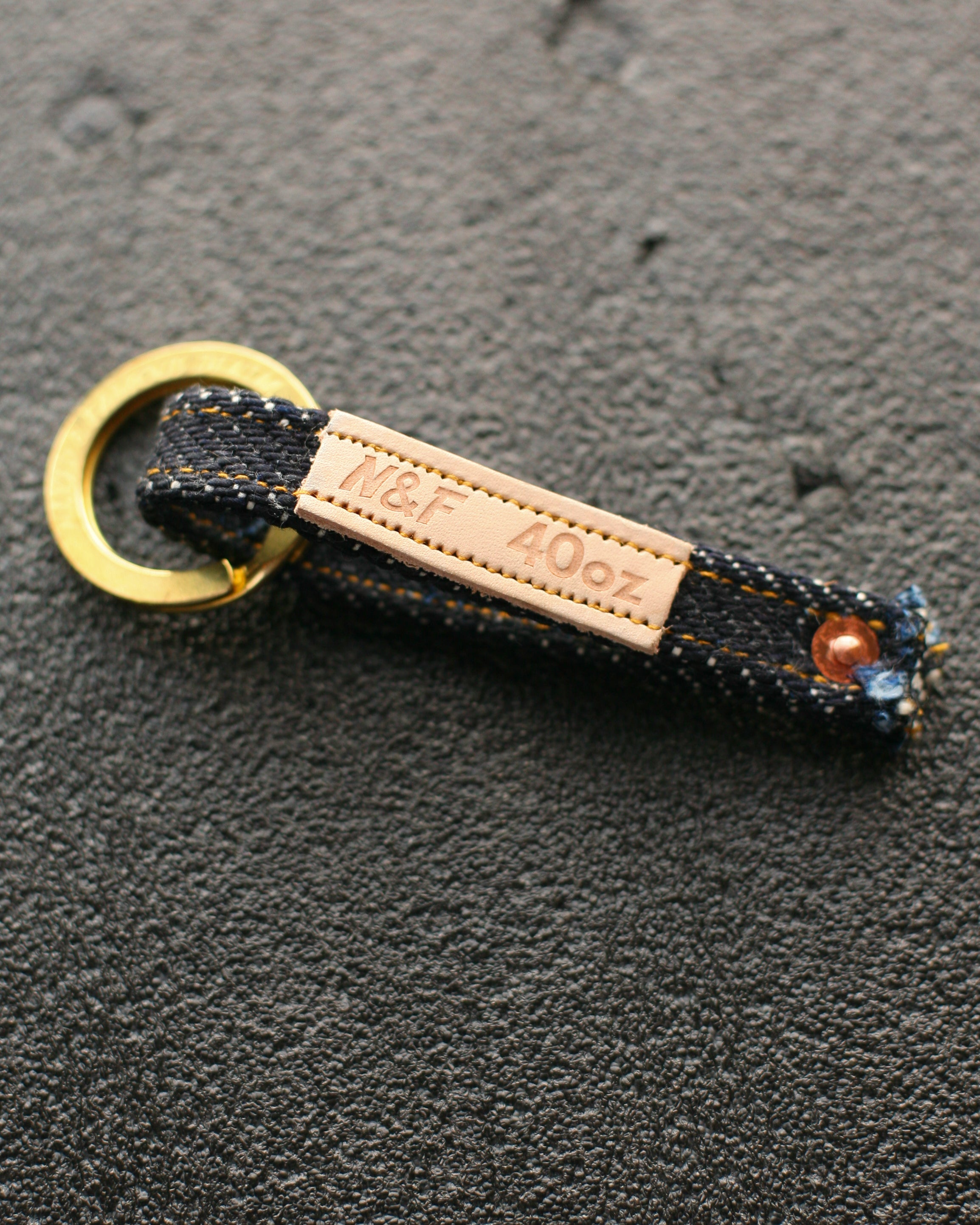 Keychain with gold ring and leather tag on a dark surface